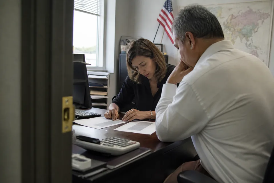 Immigration attorney and office manager comparing two software quotes at a desk